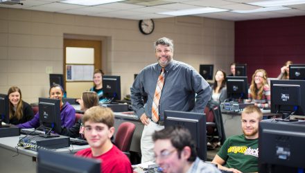 Information Systems Degree Professor and students in computer lab smiling