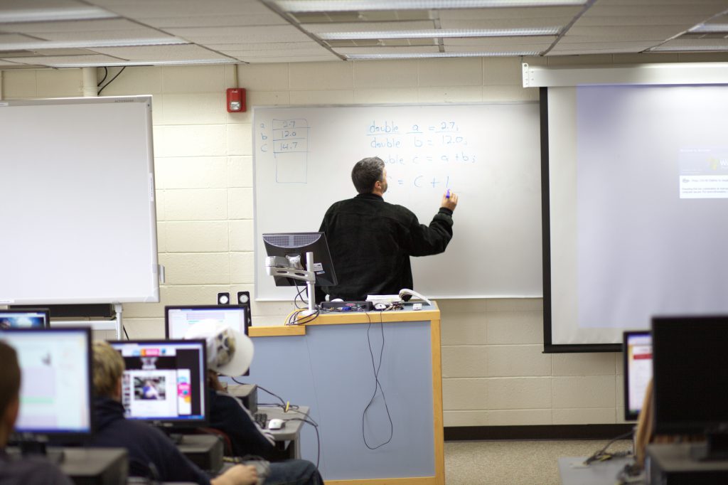 Professor in computer lab writing math on the whiteboard