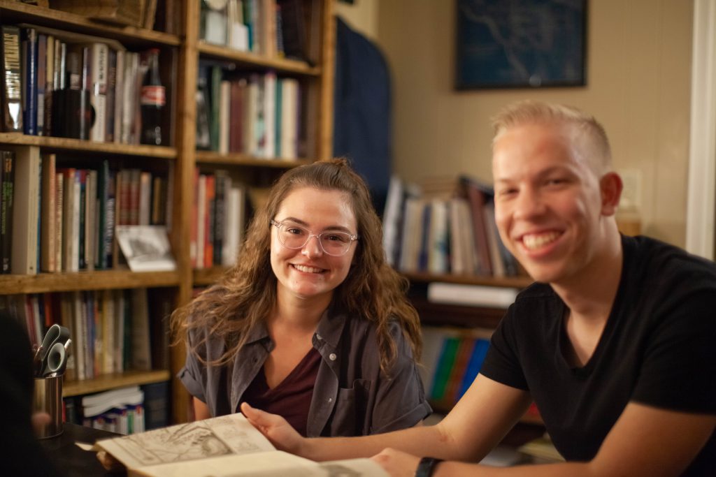 Students in professors office smiling