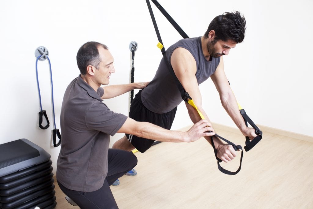 Exercise trainer with man working out at college for physical therapy