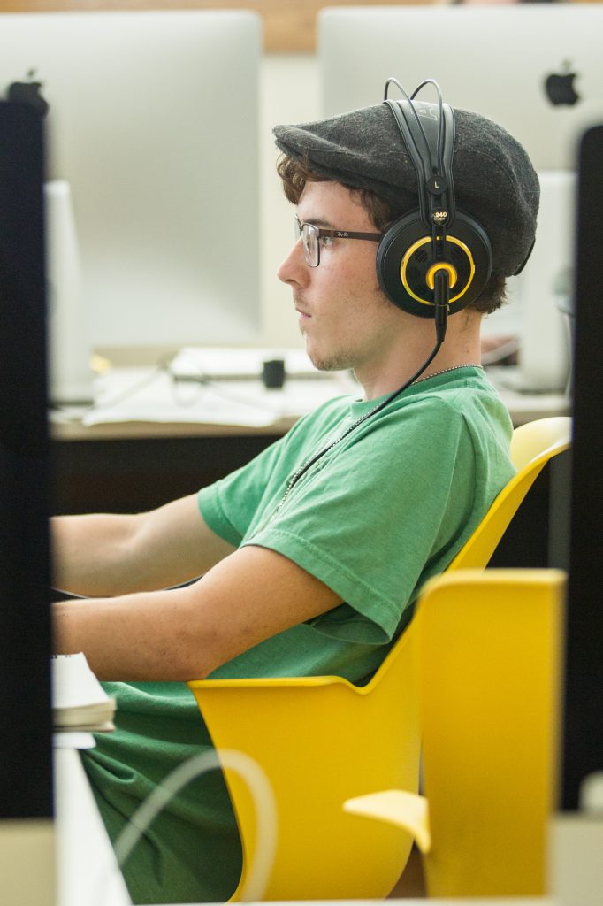 Student working on computer with headphones on