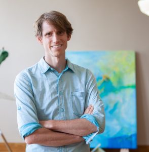 Henrik Söderström poses in front of his exhibit in the Art Gallery of Mount Memorial.
