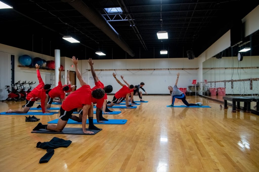 Stop #3: The Aerobics Room  Did you know that Grace provides free group fitness classes during the school year at its health and fitness center? These classes take place at a variety of times to fit your schedule and meet a variety of fitness levels and needs. Some of our classes include Athletic Yoga, p90X, Strong, and Piyo. Oh...and we cannot forget the ever-popular Zumba classes in the evening! Find a complete list on our GHAWC Facebook page! All of this, and more, takes place in our 2,800 square-foot aerobics room complete with a wood floor and wall-mounted ballet bars. Stop #4: The Fieldhouse Our fieldhouse is a 32,000 square-foot enclosed room which includes four basketball courts, an 80-yard six-lane straight track, a 1/10 mile four-lane indoor oval track, volleyball nets and two batting cages. This room serves many purposes for the Grace College and Warsaw community. It transforms into a boat-part store and boat-assembly station for our annual freshman event The Hike.  The GHAWC houses our annual Lancer camps where kids from the community develop their athletic skills under the coaching of our Lancer athletes.  It is the setting for our intramural basketball and volleyball games that take place at 9 p.m. - 11:50 p.m. on weeknights. (Did we mention college shakes things up for the sleepy-heads?) And it is also where many events for our campus-wide competition, The Joust, take place -- whether it be a 90-player game of knock out, an obstacle race, or a spikeball show-down. The GHAWC also transforms into a children’s marketplace where community kids’ clothing and toys are sold to raise money for Kid’s Market Inc.  Stop #5: The Athletic Performance Room Tucked behind our frequented fitness room is a space that our varsity athletic teams utilize on a regular basis for team training and meetings. This 1,300 square-foot Athletic Performance room contains Hammer Strength combo racks, a full set of DB free weights, Vertimax trainer, and plenty of agility equipment located on a turf flooring. Stop #6: The Golf Room Some might not know about the state-of-the-art indoor putting green we have! This is the perfect space for our golf players to “tee-it-up” on a cold or rainy day when the course is closed! So now that we’ve “taken you around” the health and fitness center, you should know that the GHAWC is not just for Grace students. The way of Grace leads us to be generous with what we’ve been given, so we’ve extended the invitation to several additional groups in our community: Grace College & Seminary employees and their spouses Grace College & Seminary alumni and their spouses Community senior citizens – age 60 and up (must obtain medical release) Local law enforcement and fire/ems personnel If you fall into one of these categories, (hopefully!) we will see you at the health and fitness center soon!