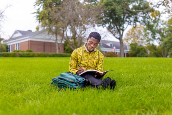 Student studying on the lawn in front of McClain hall. Devotionals for college students. Grace College wants you to grow in your faith and knowledge of God. Come Discover our Christian College.