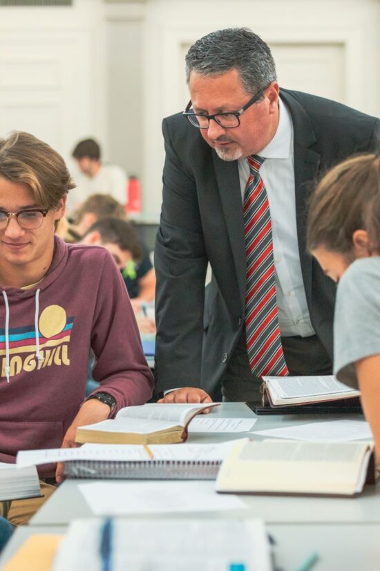 A Grace College professor engaging with students in a classroom, providing guidance and mentorship over study materials.