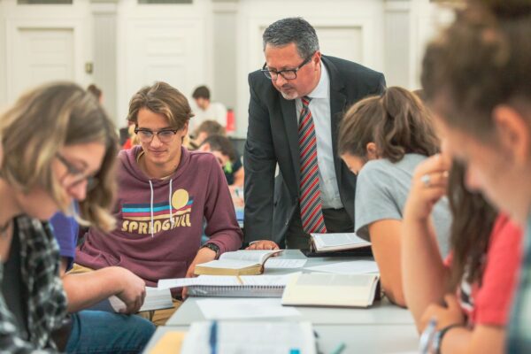 A Grace College professor engaging with students in a classroom, providing guidance and mentorship over study materials.