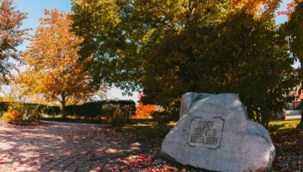 Large engraved rock on Grace College a Christian college campus surrounded by colorful autumn trees and fallen leaves, symbolizing heritage and faith-centered tradition.